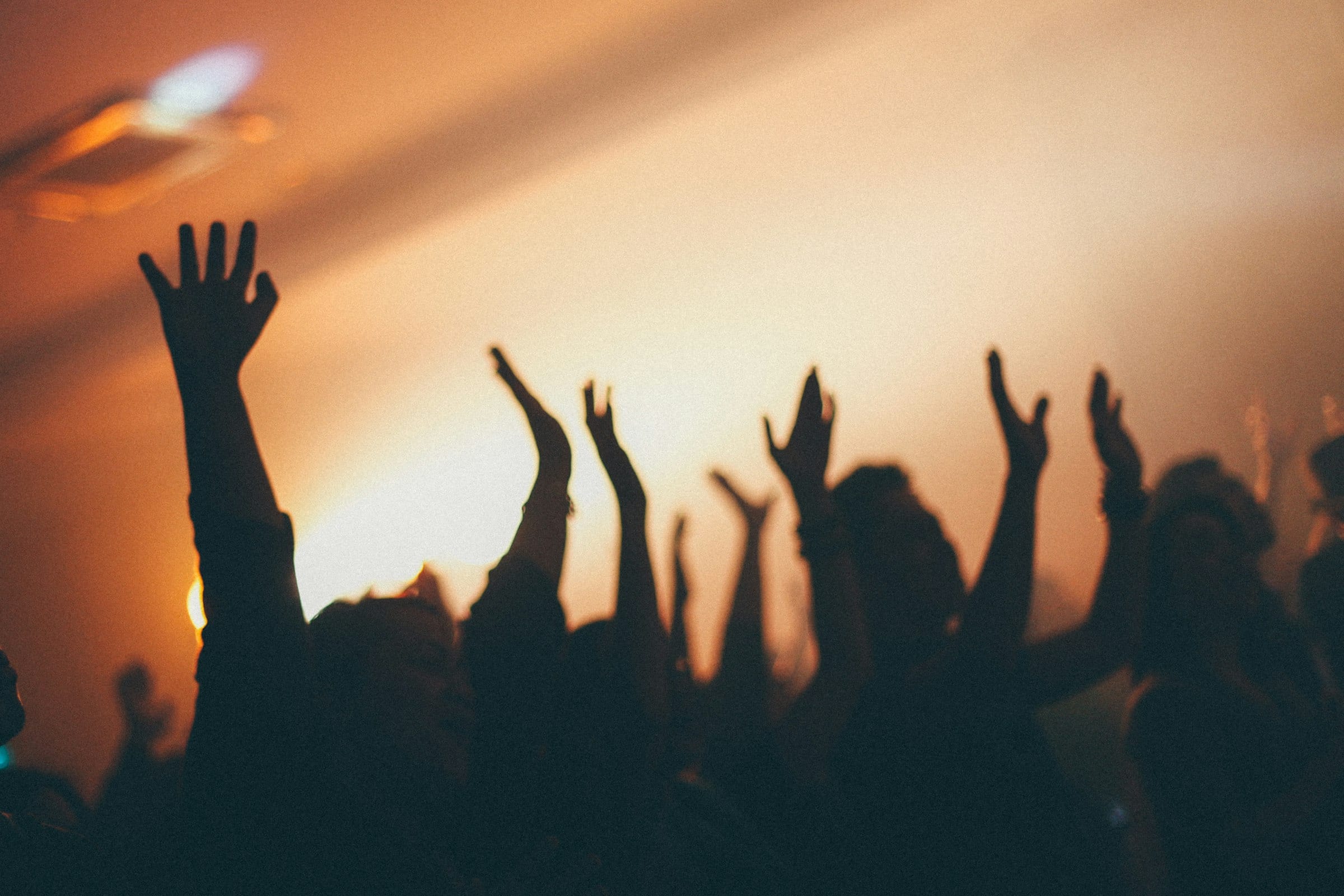 Hands raised in worship, silhouetted against warm light